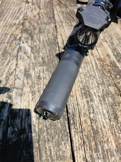 Dead Air Sierra 5 suppressor mounted on a scoped rifle resting on a weathered wooden bench, viewed down the barrel toward the muzzle
